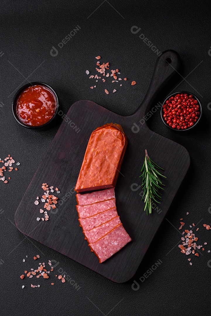 Delicioso salame de salsicha fresca com sal, tomate e especiarias sobre um fundo escuro de concreto