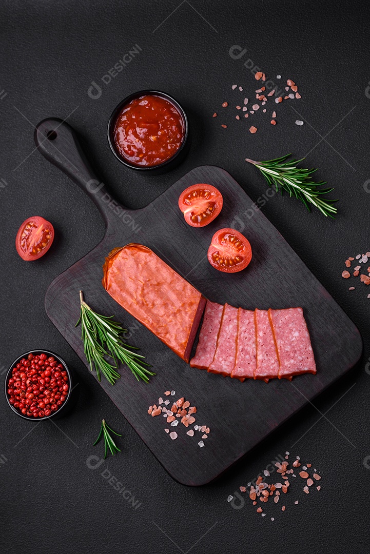 Delicioso salame de salsicha fresca com sal, tomate e especiarias sobre um fundo escuro de concreto