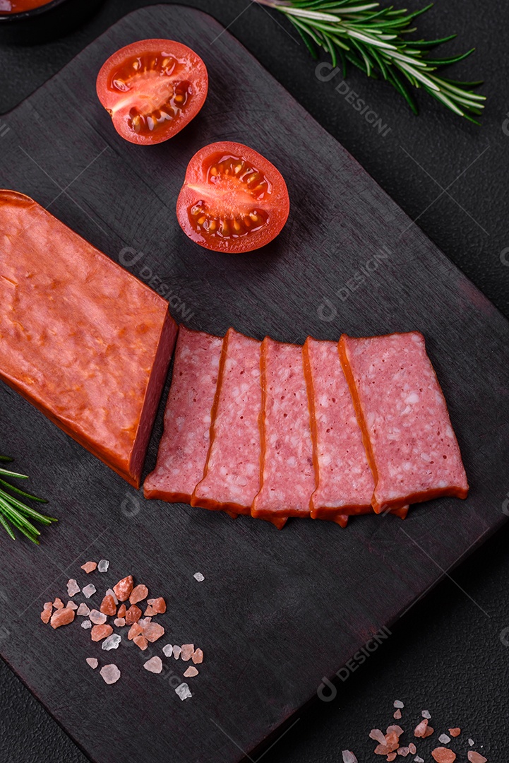 Delicioso salame de salsicha fresca com sal, tomate e especiarias sobre um fundo escuro de concreto