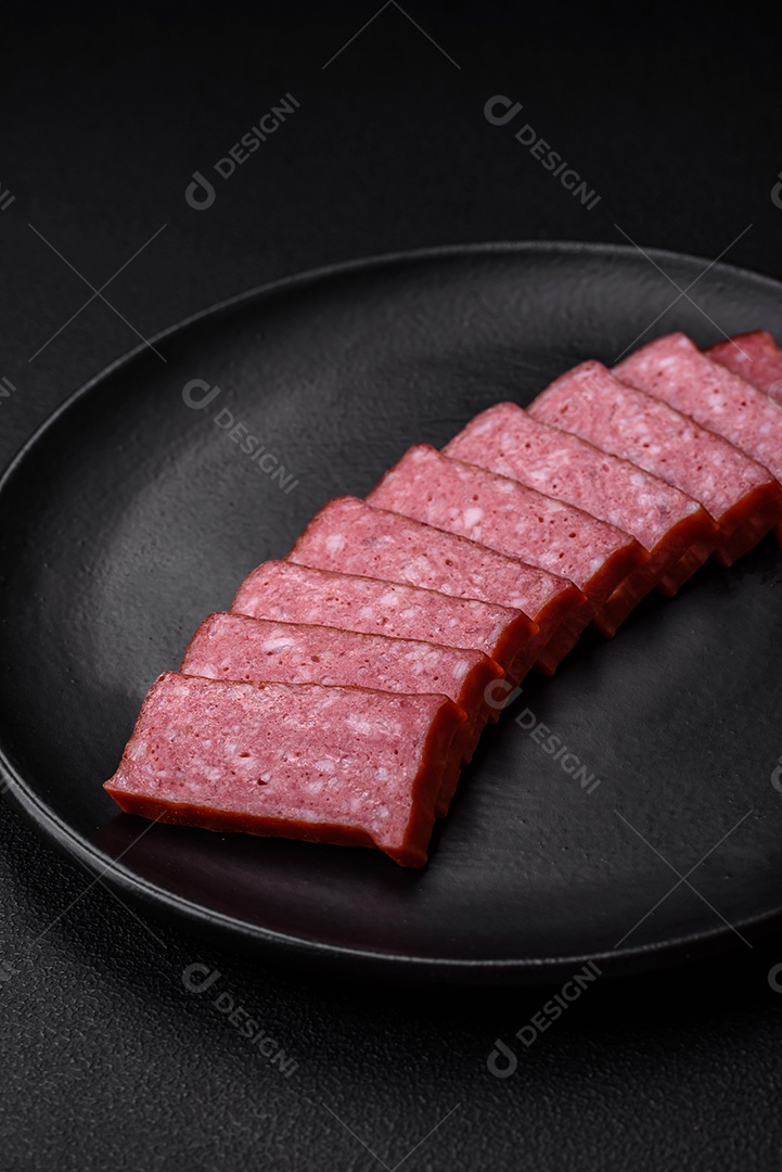 Delicioso salame de salsicha fresca com sal, tomate e especiarias sobre um fundo escuro de concreto