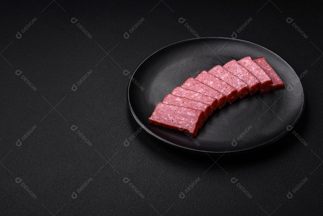 Delicioso salame de salsicha fresca com sal, tomate e especiarias sobre um fundo escuro de concreto