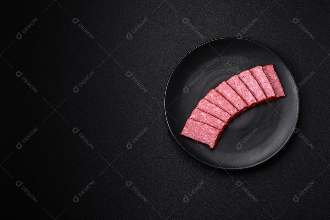 Delicioso salame de salsicha fresca com sal, tomate e especiarias sobre um fundo escuro de concreto