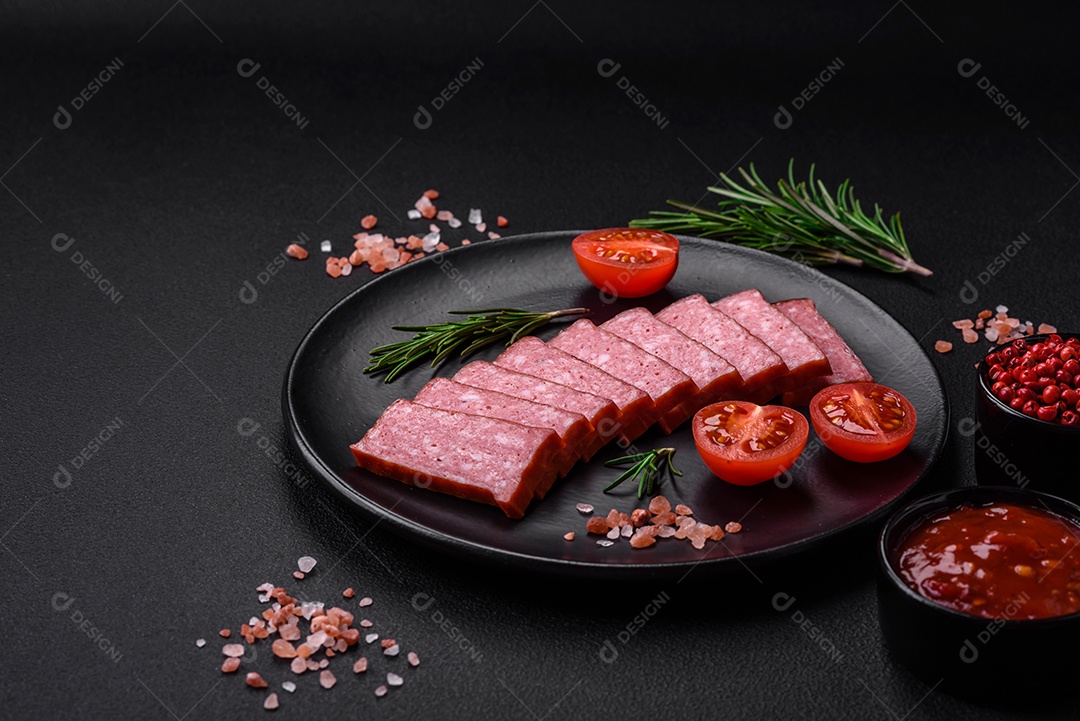 Delicioso salame de salsicha fresca com sal, tomate e especiarias sobre um fundo escuro de concreto