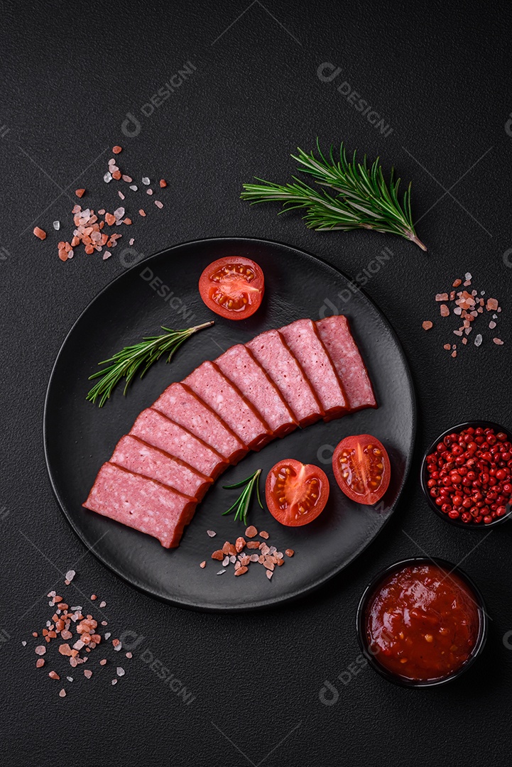 Delicioso salame de salsicha fresca com sal, tomate e especiarias sobre um fundo escuro de concreto
