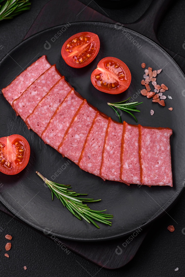 Delicioso salame de salsicha fresca com sal, tomate e especiarias sobre um fundo escuro de concreto