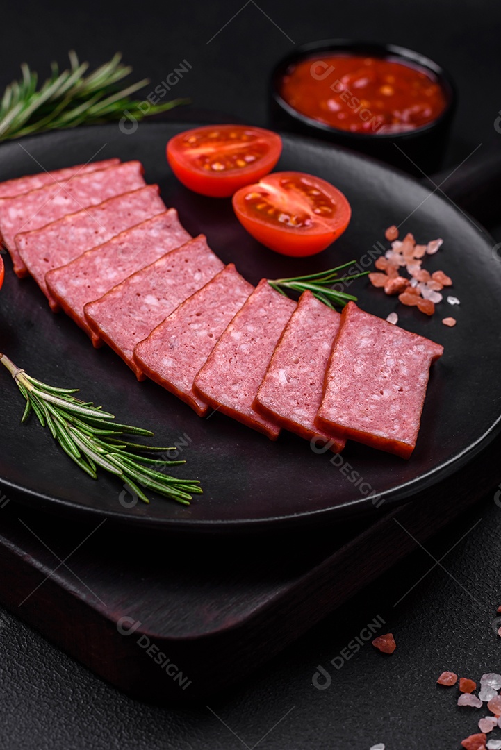 Delicioso salame de salsicha fresca com sal, tomate e especiarias sobre um fundo escuro de concreto