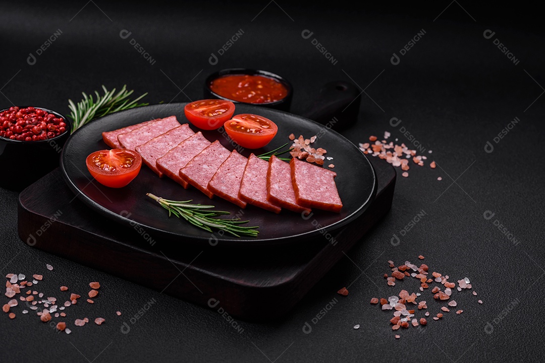 Delicioso salame de salsicha fresca com sal, tomate e especiarias sobre um fundo escuro de concreto
