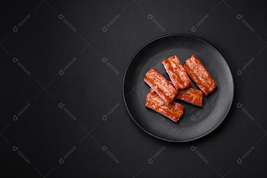 Costelas suculentas frescas grelhadas com sal, especiarias e ervas sobre um fundo escuro de concreto