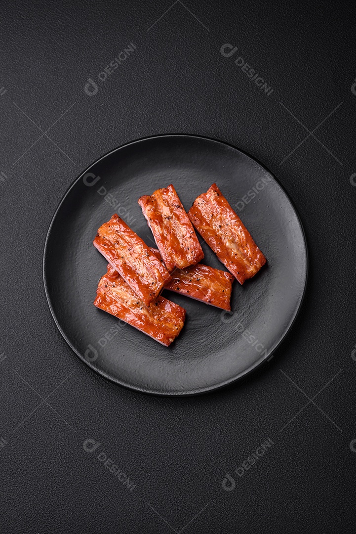 Costelas suculentas frescas grelhadas com sal, especiarias e ervas sobre um fundo escuro de concreto