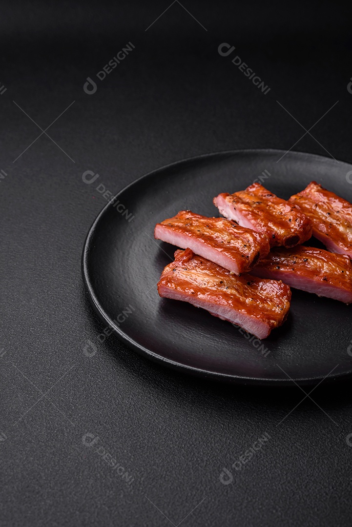 Costelas suculentas frescas grelhadas com sal, especiarias e ervas sobre um fundo escuro de concreto