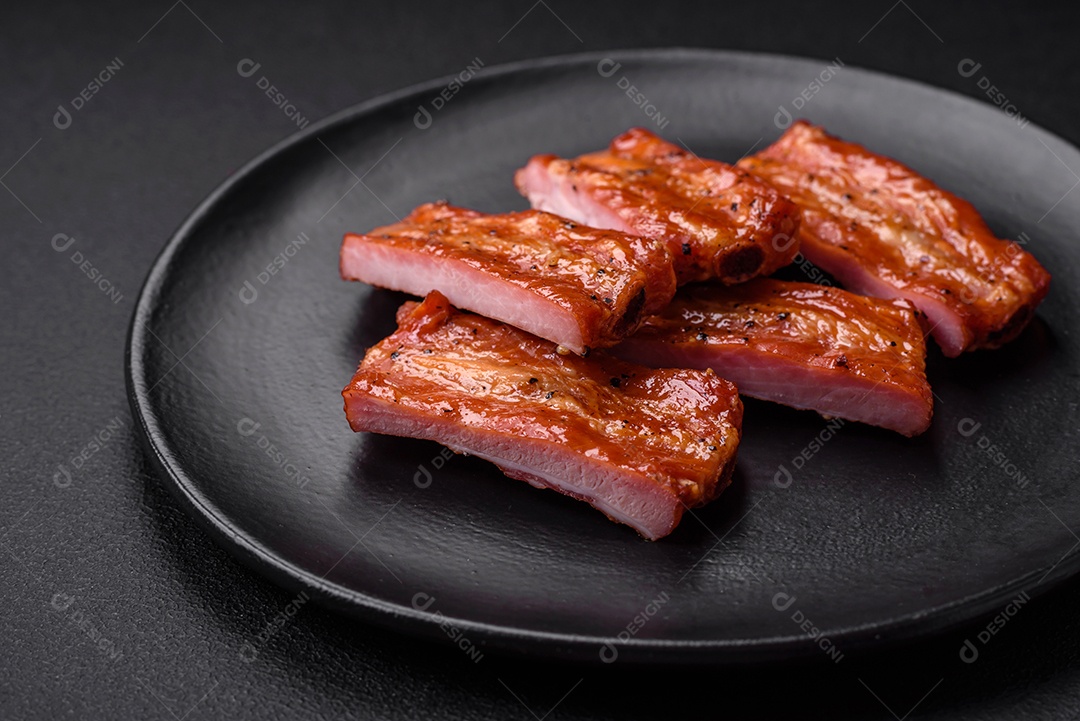 Costelas suculentas frescas grelhadas com sal, especiarias e ervas sobre um fundo escuro de concreto