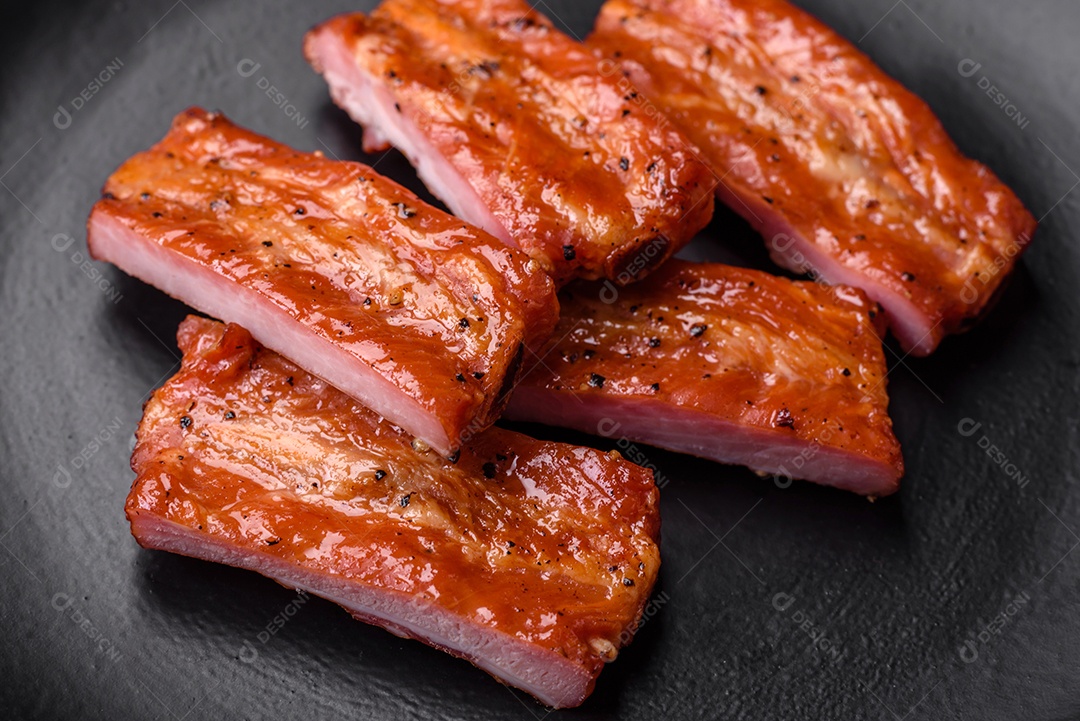 Costelas suculentas frescas grelhadas com sal, especiarias e ervas sobre um fundo escuro de concreto