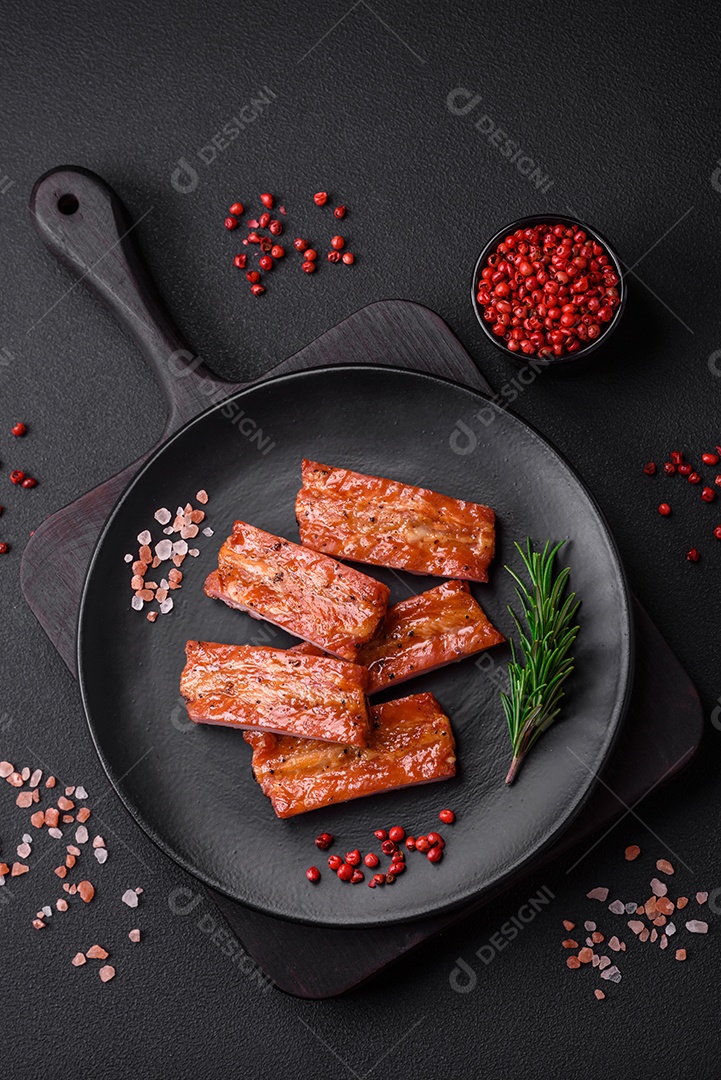 Costelas suculentas frescas grelhadas com sal, especiarias e ervas sobre um fundo escuro de concreto