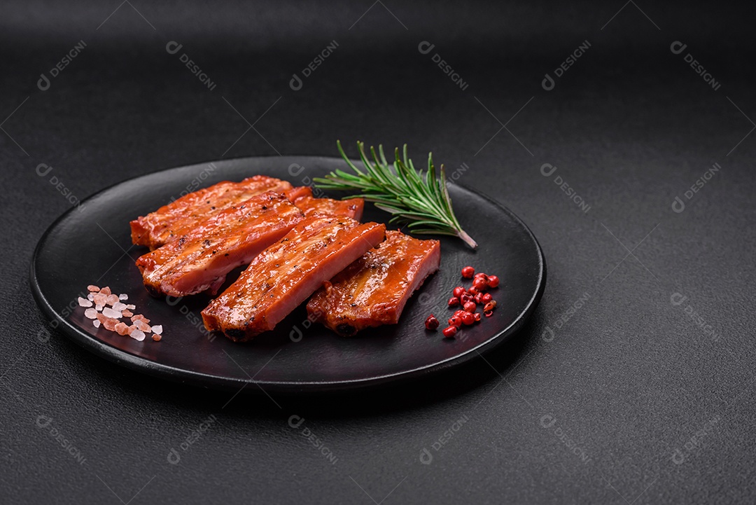Costelas suculentas frescas grelhadas com sal, especiarias e ervas sobre um fundo escuro de concreto