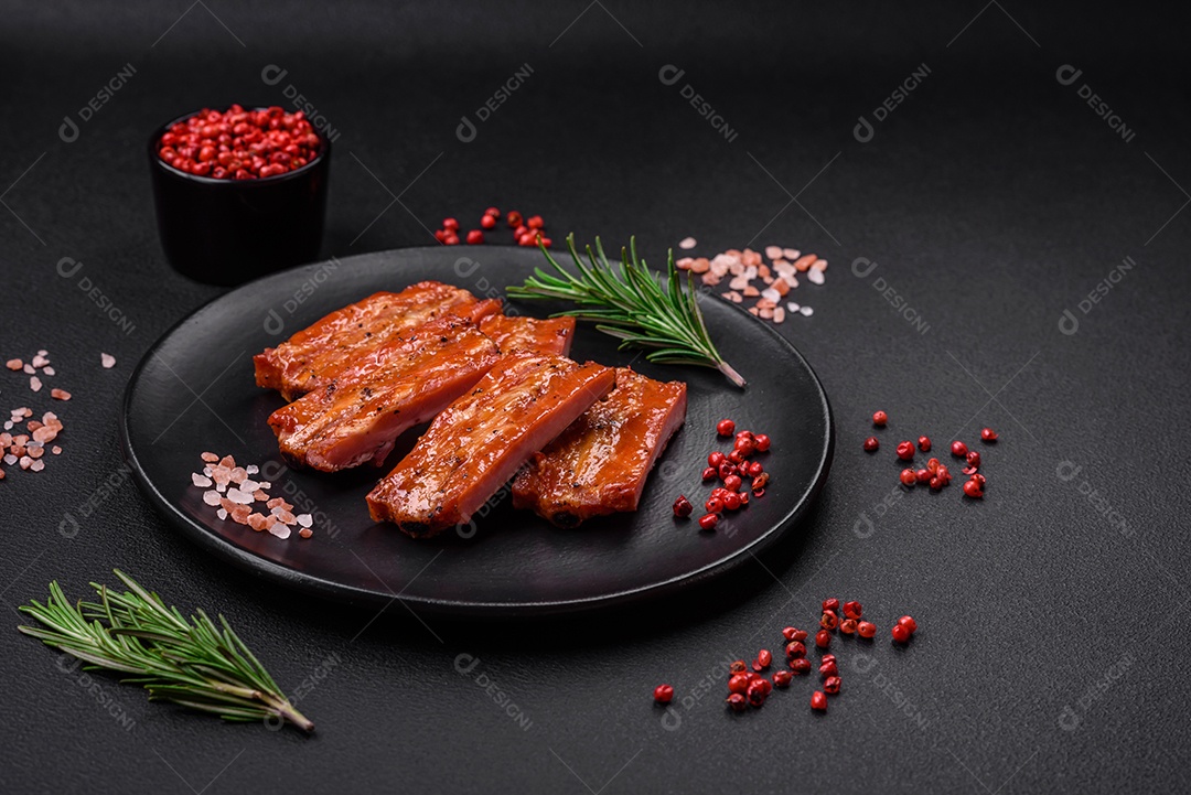 Costelas suculentas frescas grelhadas com sal, especiarias e ervas sobre um fundo escuro de concreto