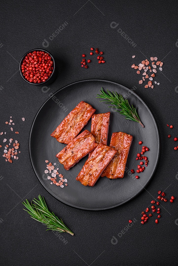 Costelas suculentas frescas grelhadas com sal, especiarias e ervas sobre um fundo escuro de concreto