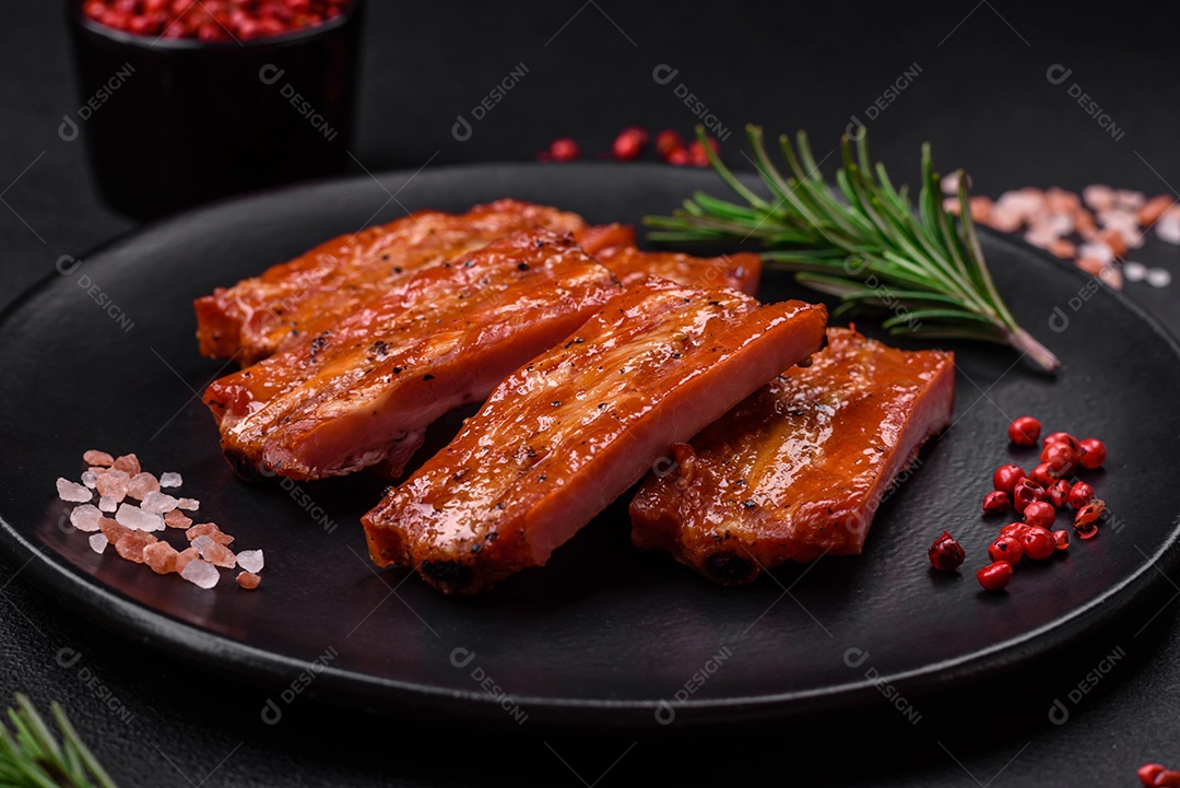 Costelas suculentas frescas grelhadas com sal, especiarias e ervas sobre um fundo escuro de concreto