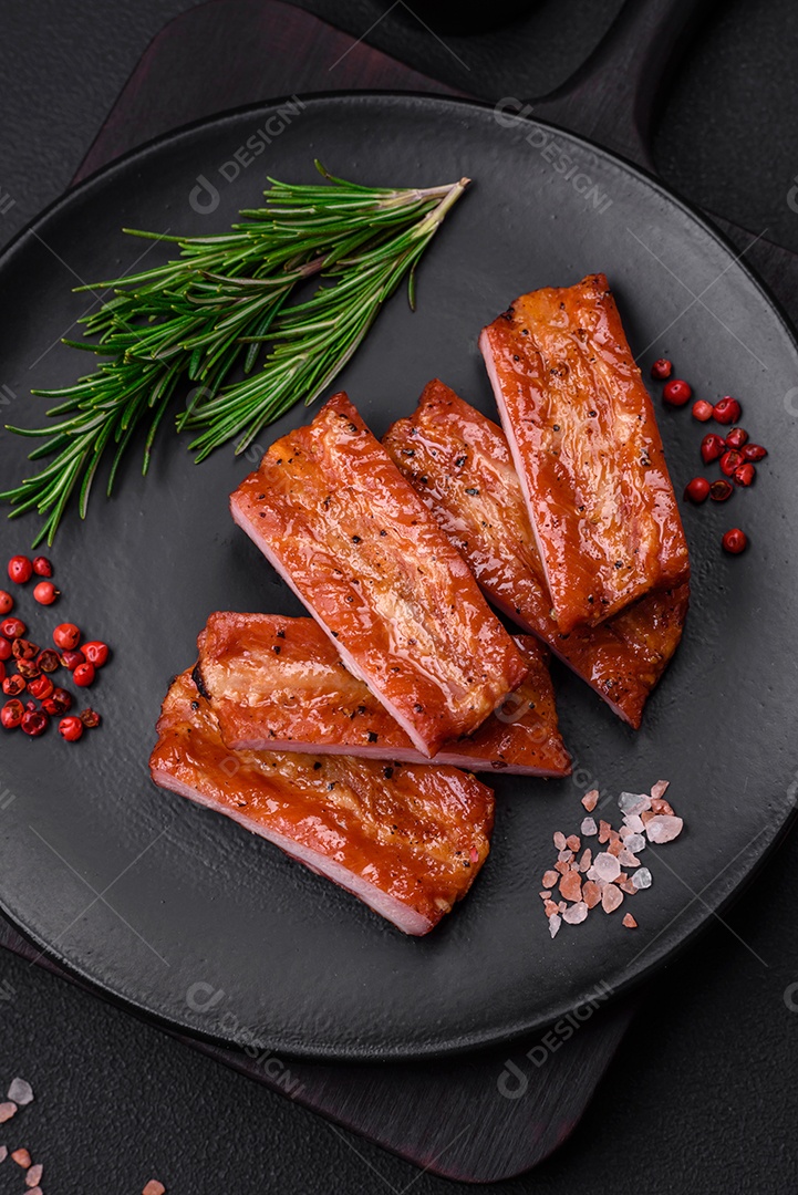 Costelas suculentas frescas grelhadas com sal, especiarias e ervas sobre um fundo escuro de concreto