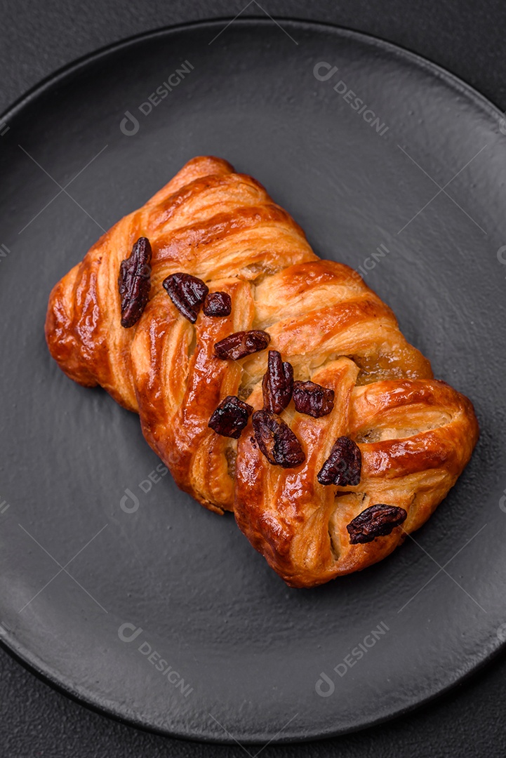 Delicioso pão de trança recém-assado com nozes e xarope sobre um fundo escuro de concreto