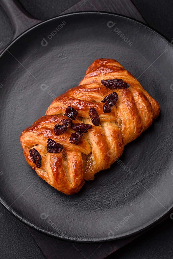 Delicioso pão de trança recém-assado com nozes e xarope sobre um fundo escuro de concreto