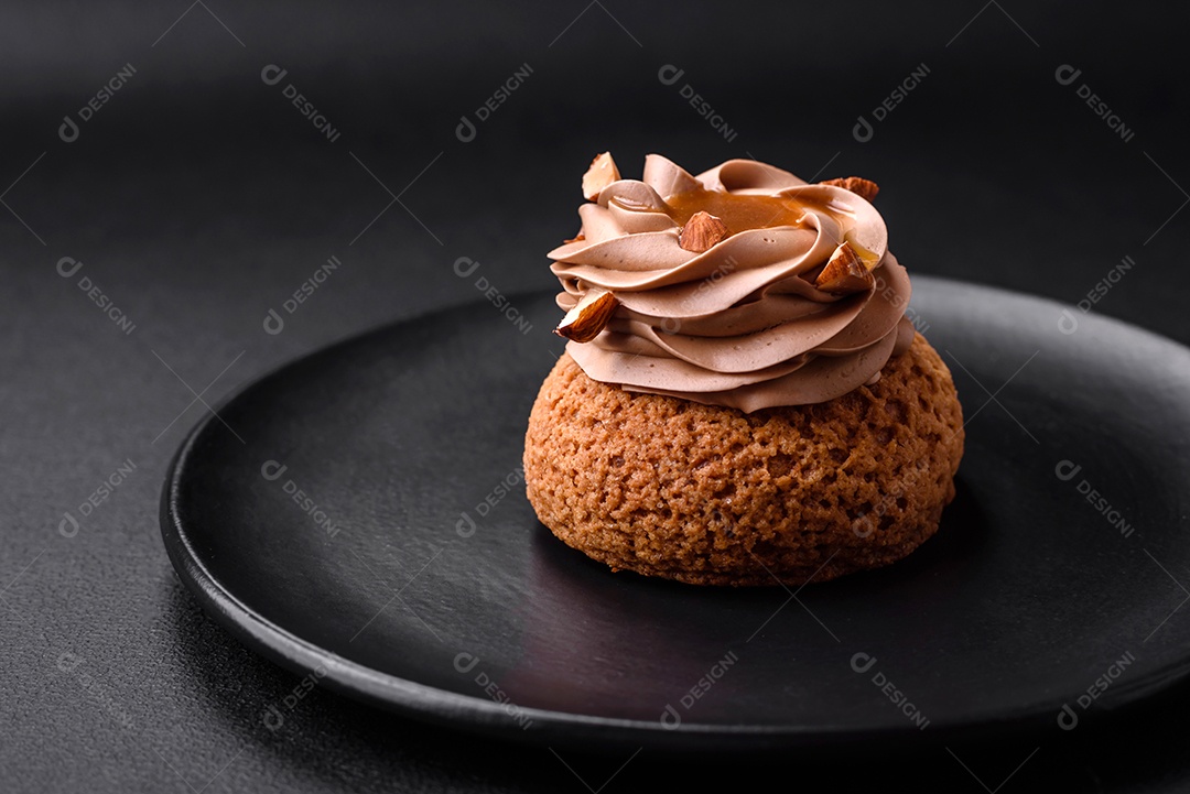 Delicioso bolo doce shu com creme e nozes sobre um fundo escuro de concreto