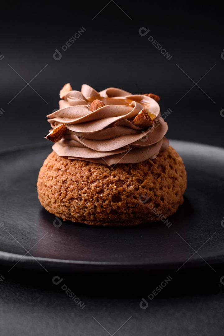 Delicioso bolo doce shu com creme e nozes sobre um fundo escuro de concreto