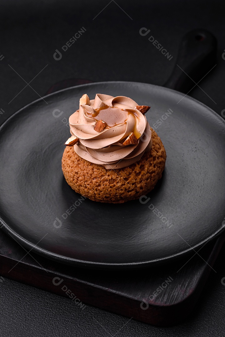 Delicioso bolo doce shu com creme e nozes sobre um fundo escuro de concreto