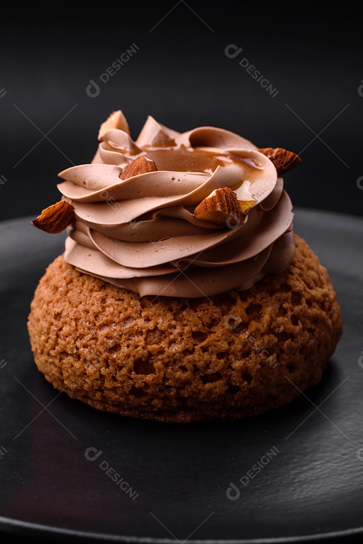 Delicioso bolo doce shu com creme e nozes sobre um fundo escuro de concreto