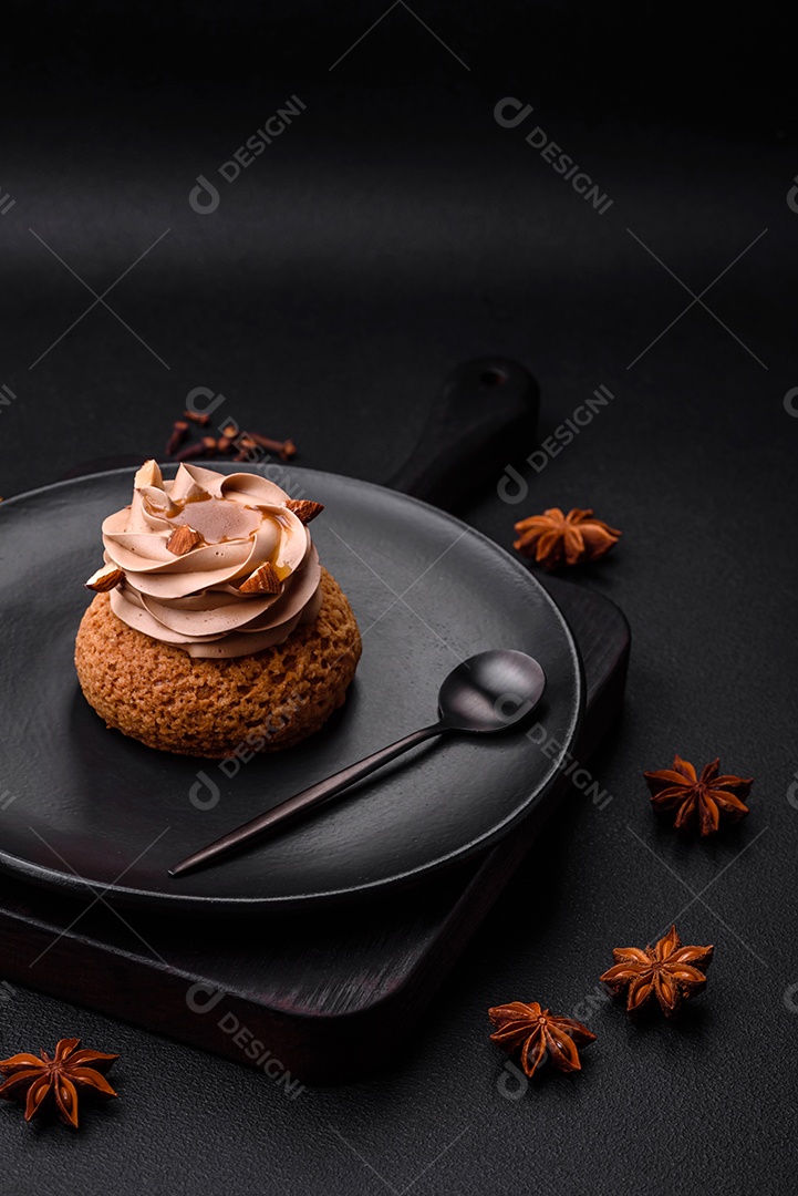 Delicioso bolo doce shu com creme e nozes sobre um fundo escuro de concreto