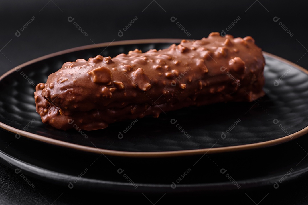 Delicioso bolo éclair fresco ou profiterole com chocolate e nozes sobre um fundo escuro de concreto