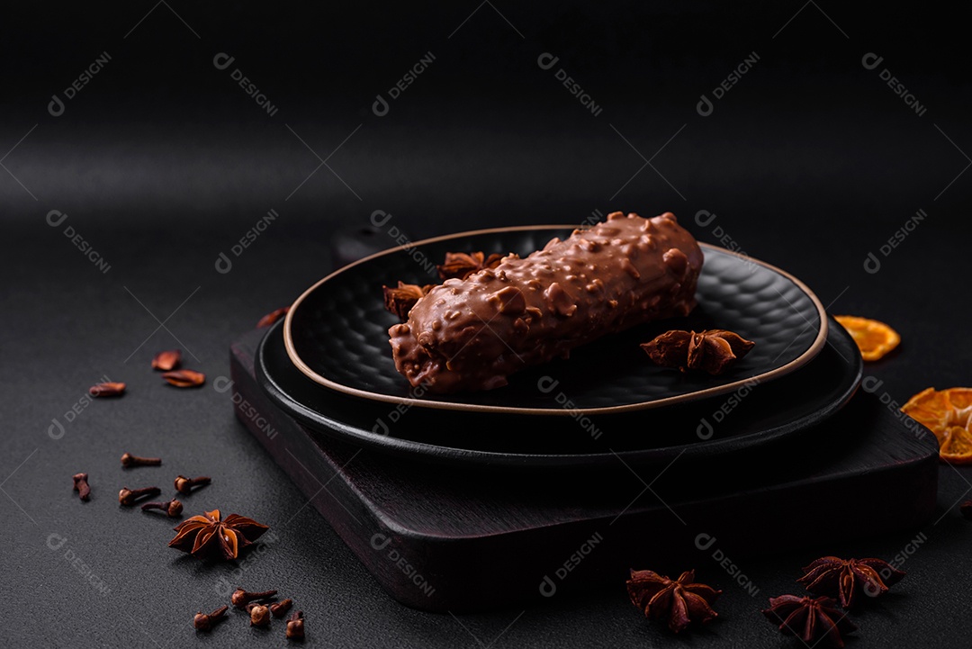 Delicioso bolo éclair fresco ou profiterole com chocolate e nozes sobre um fundo escuro de concreto