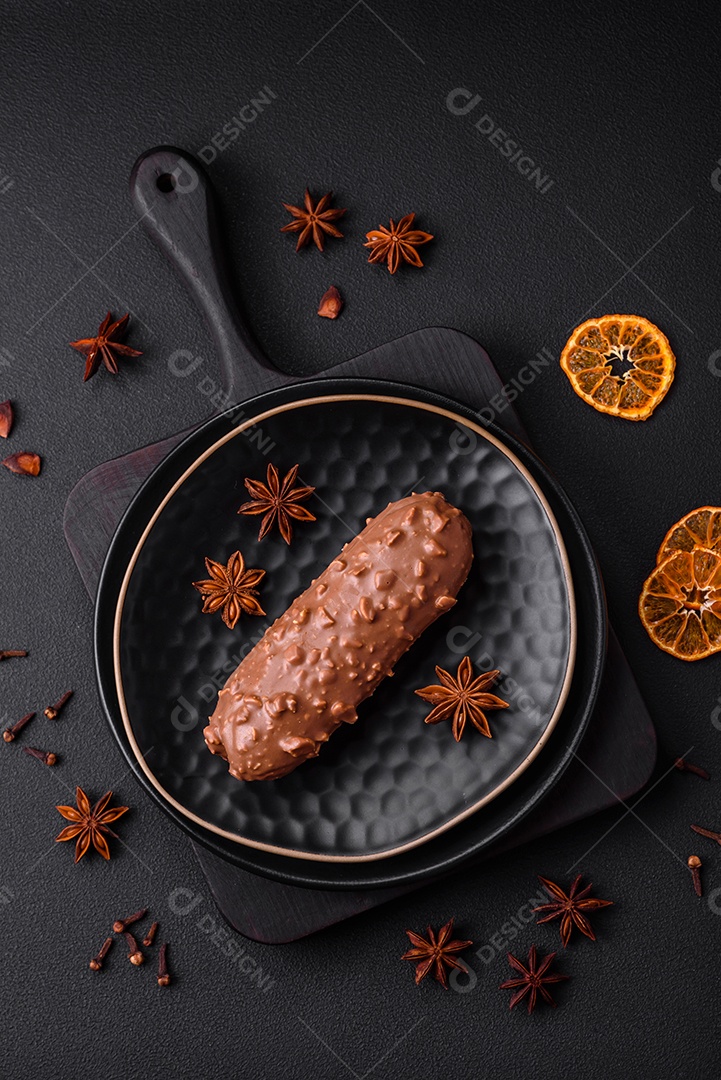 Delicioso bolo éclair fresco ou profiterole com chocolate e nozes sobre um fundo escuro de concreto