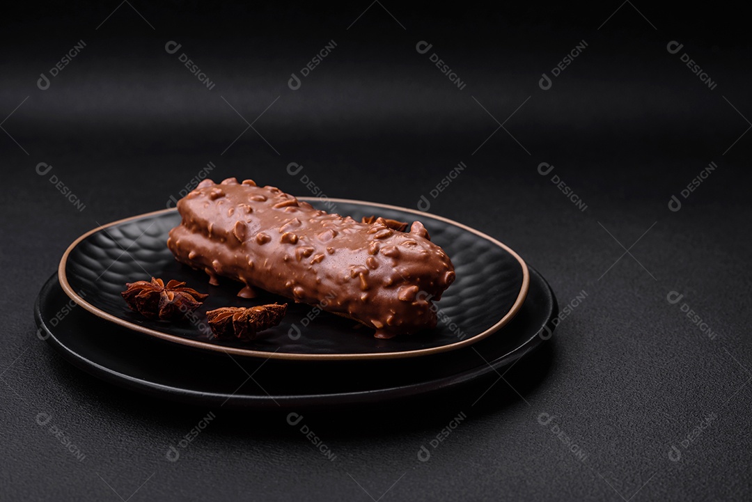 Delicioso bolo éclair fresco ou profiterole com chocolate e nozes sobre um fundo escuro de concreto