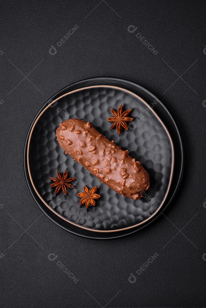 Delicioso bolo éclair fresco ou profiterole com chocolate e nozes sobre um fundo escuro de concreto