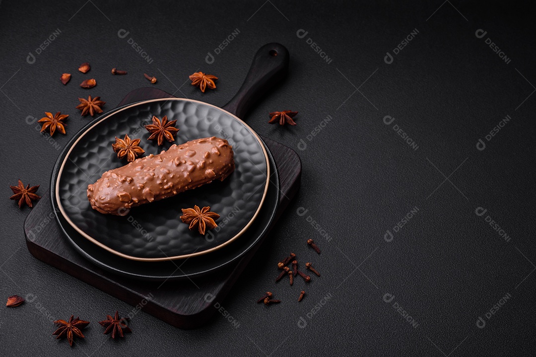 Delicioso bolo éclair fresco ou profiterole com chocolate e nozes sobre um fundo escuro de concreto