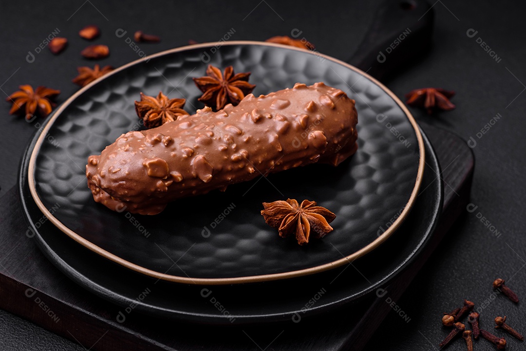 Delicioso bolo éclair fresco ou profiterole com chocolate e nozes sobre um fundo escuro de concreto