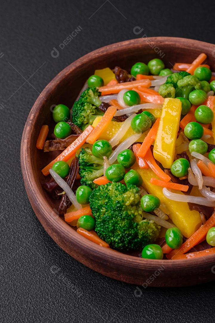 Deliciosos legumes cozidos no vapor, brócolis, cogumelos, ervilhas, cenouras e cebolas sobre um fundo escuro de concreto