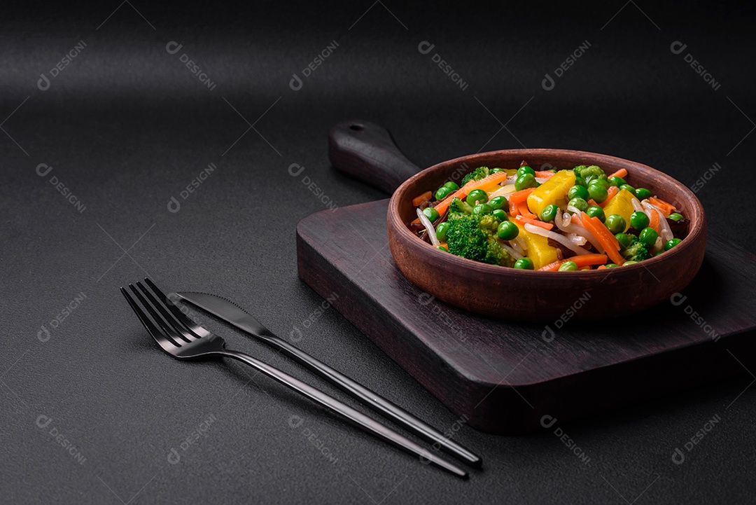 Deliciosos legumes cozidos no vapor, brócolis, cogumelos, ervilhas, cenouras e cebolas sobre um fundo escuro de concreto