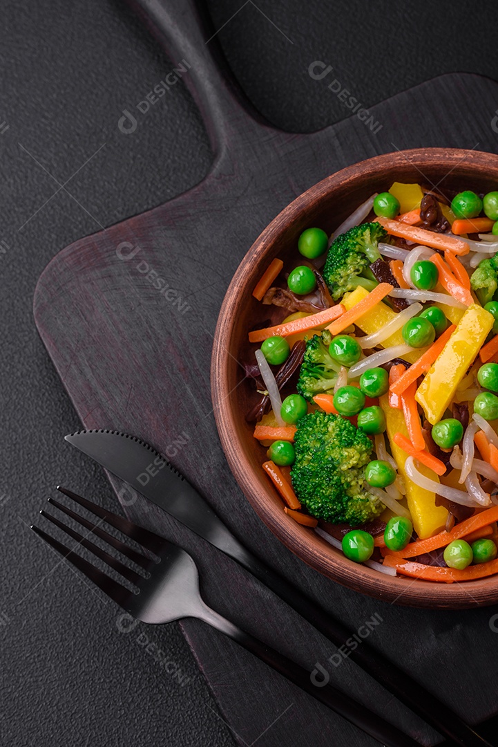 Deliciosos legumes cozidos no vapor, brócolis, cogumelos, ervilhas, cenouras e cebolas sobre um fundo escuro de concreto
