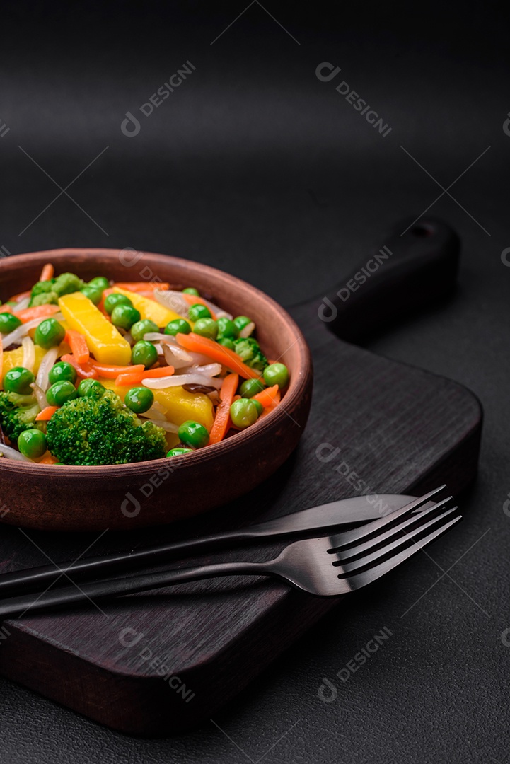 Deliciosos legumes cozidos no vapor, brócolis, cogumelos, ervilhas, cenouras e cebolas sobre um fundo escuro de concreto