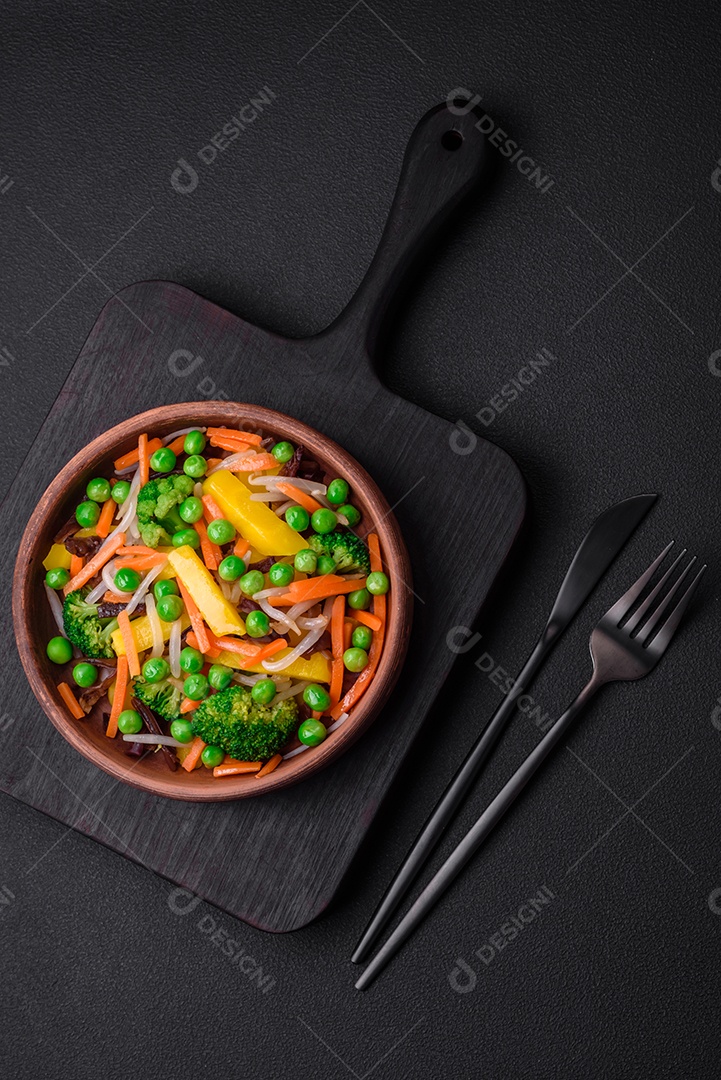 Deliciosos legumes cozidos no vapor, brócolis, cogumelos, ervilhas, cenouras e cebolas sobre um fundo escuro de concreto