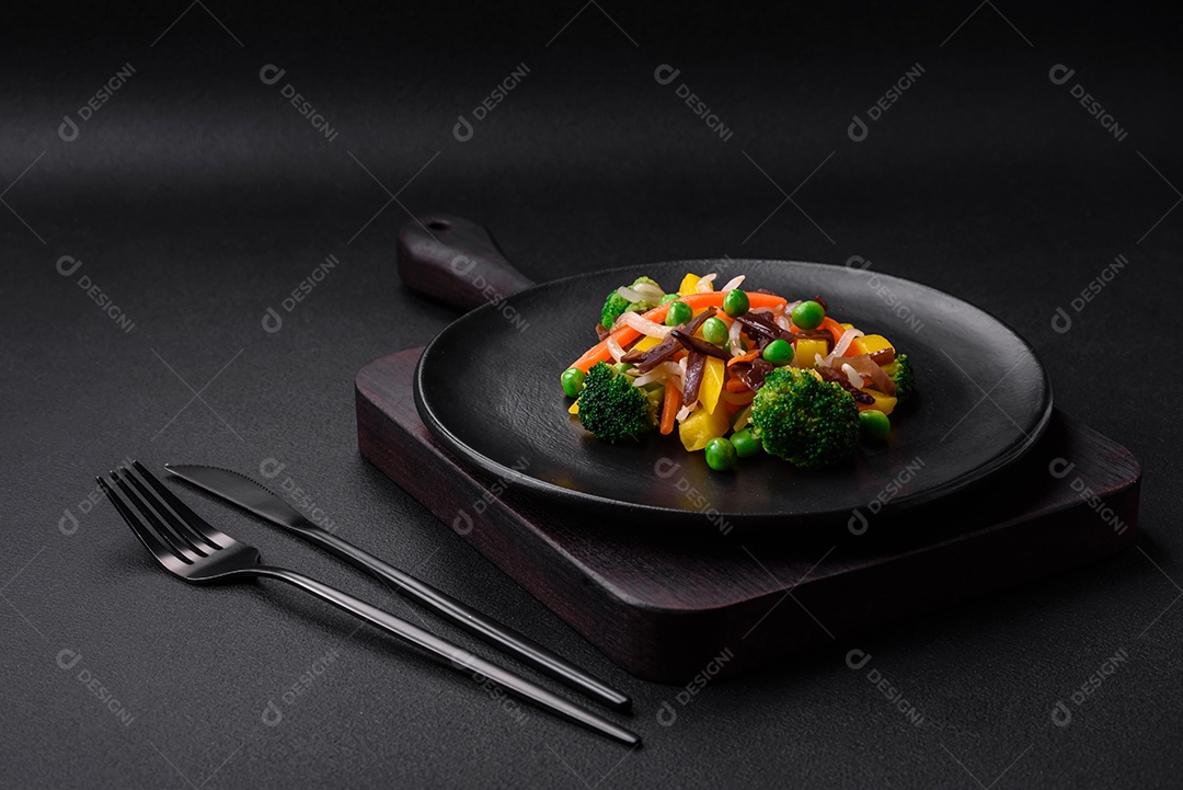 Deliciosos legumes cozidos no vapor, brócolis, cogumelos, ervilhas, cenouras e cebolas sobre um fundo escuro de concreto