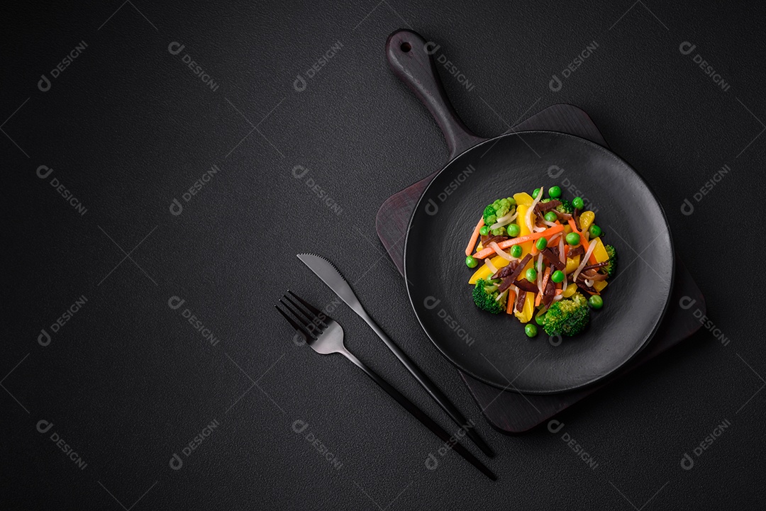 Deliciosos legumes cozidos no vapor, brócolis, cogumelos, ervilhas, cenouras e cebolas sobre um fundo escuro de concreto