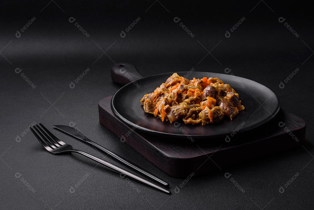 Deliciosas moelas de frango estufadas com cenoura e tomate sobre um fundo escuro de concreto