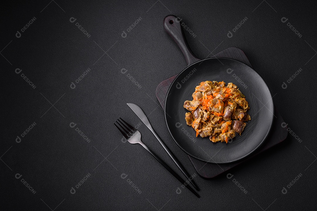 Deliciosas moelas de frango estufadas com cenoura e tomate sobre um fundo escuro de concreto