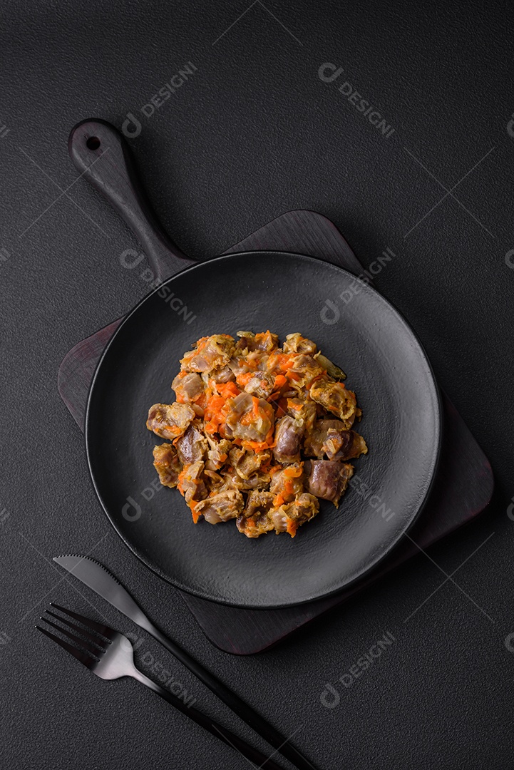 Deliciosas moelas de frango estufadas com cenoura e tomate sobre um fundo escuro de concreto
