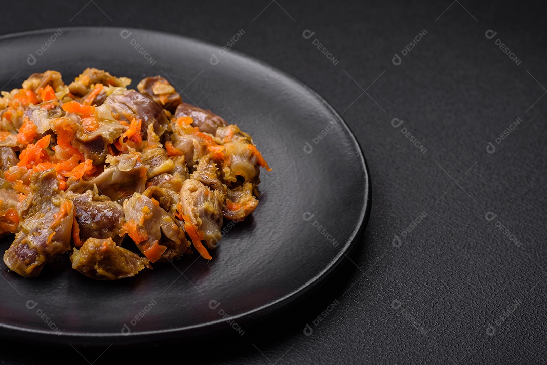 Deliciosas moelas de frango estufadas com cenoura e tomate sobre um fundo escuro de concreto