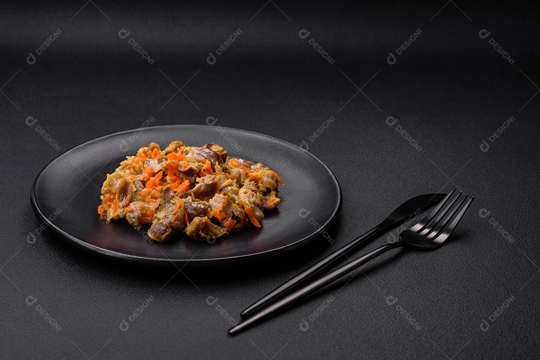 Deliciosas moelas de frango estufadas com cenoura e tomate sobre um fundo escuro de concreto