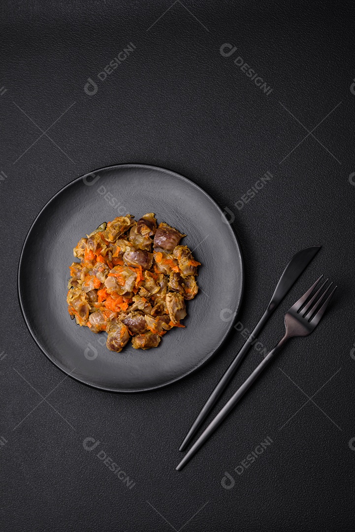 Deliciosas moelas de frango estufadas com cenoura e tomate sobre um fundo escuro de concreto