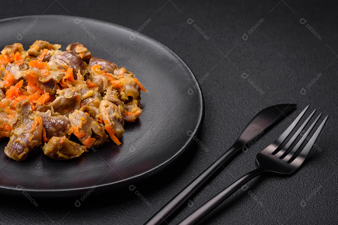 Deliciosas moelas de frango estufadas com cenoura e tomate sobre um fundo escuro de concreto